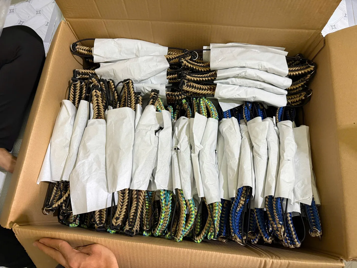A carton of finished handwoven paracord leashes wrapped and ready to ship
