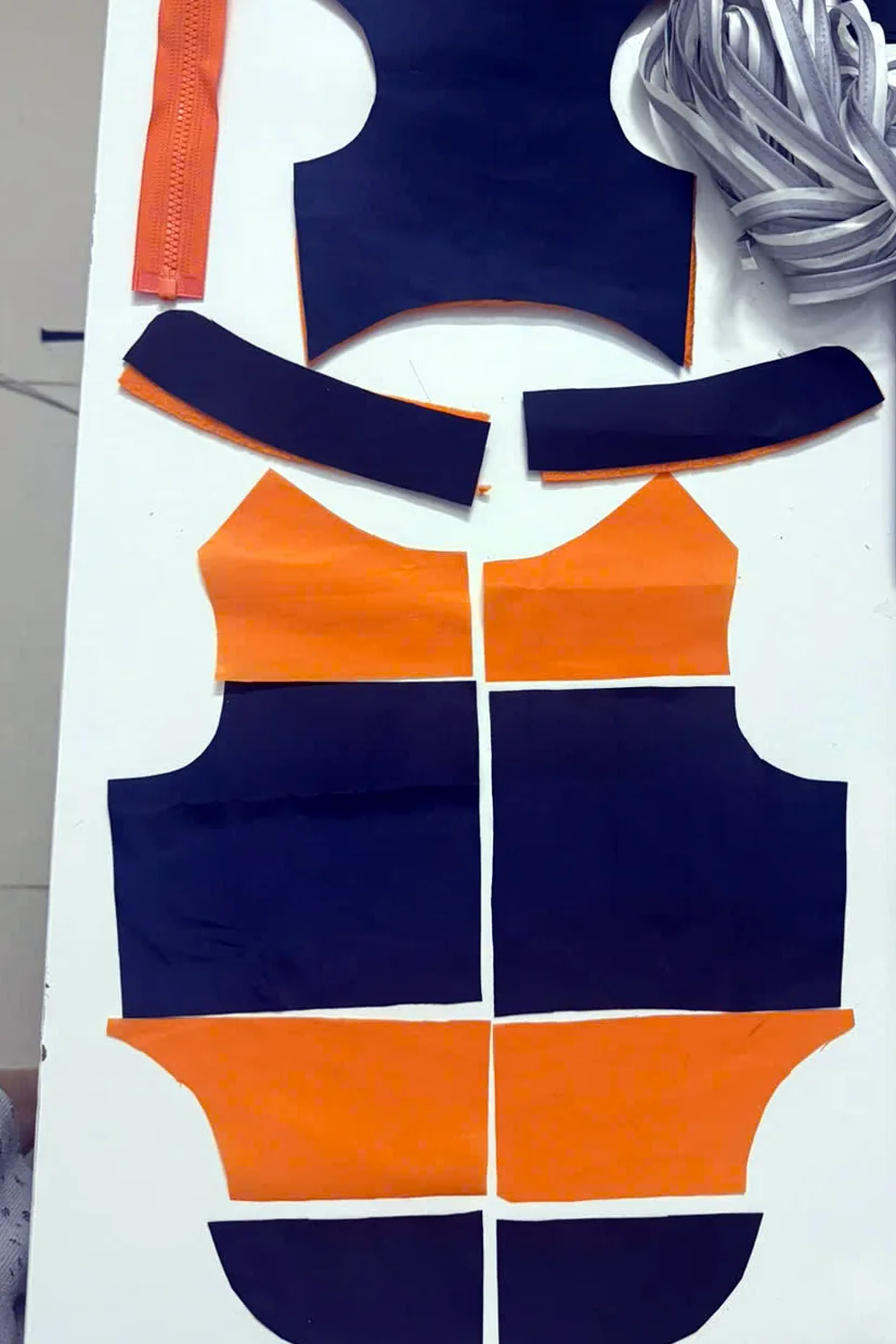 Panels for the same custom garment cut in navy and orange fabric, laid out with an orange zip and reflective trim